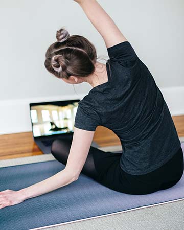 Woman practicing yoga in front of laptop