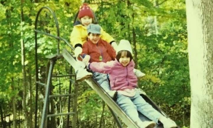 Lauren and siblings as kids on a slide 