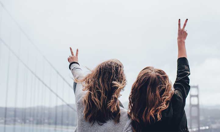 Two women raise peace sign at San Francisco Bridge