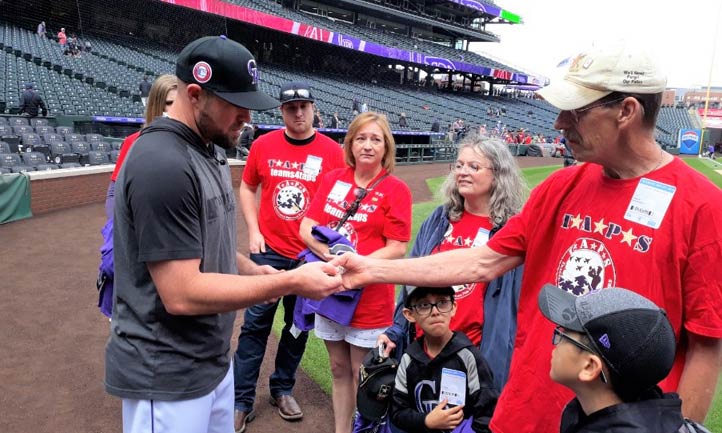 Robert Wichmann presents Colorado Rockies Mike Dunn with TAPS coin