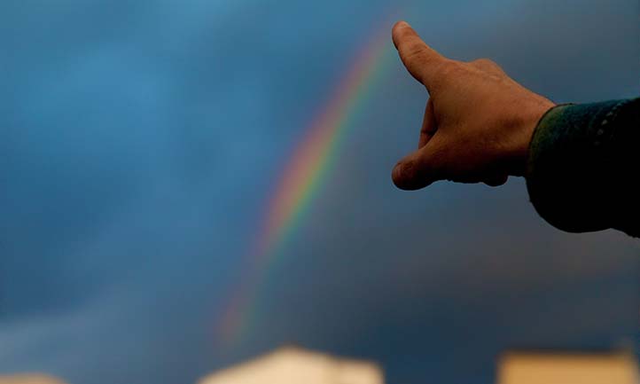 Finger pointing at rainbow