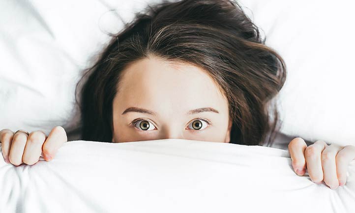 woman with bed covers over head