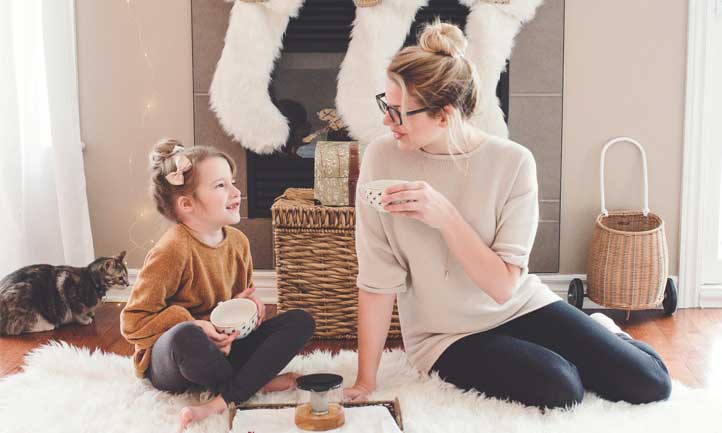 Mom and daughter in front of holiday decorated fireplace