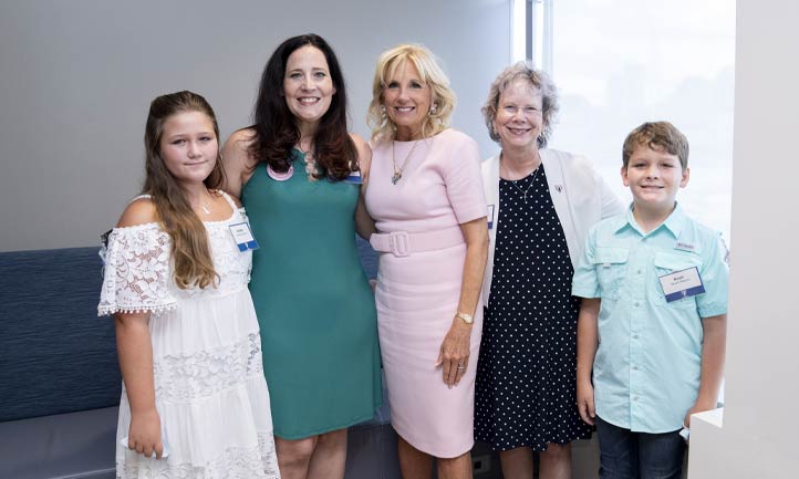 Katie Langer,and her family, daughter Natalie, mother Pat, and son Noah pose for a photo with First Lady Dr. Jill Biden during her trip to the Home Base program in July 2022