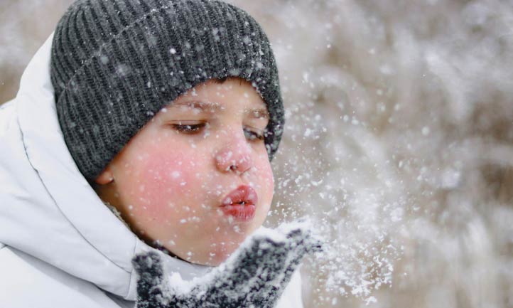 Boy blowing snow out of hand