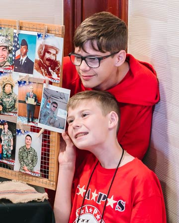 Boys pose by father's photo on hero wall