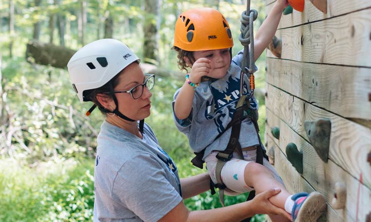 Mom helps daughter on rock climbing wall